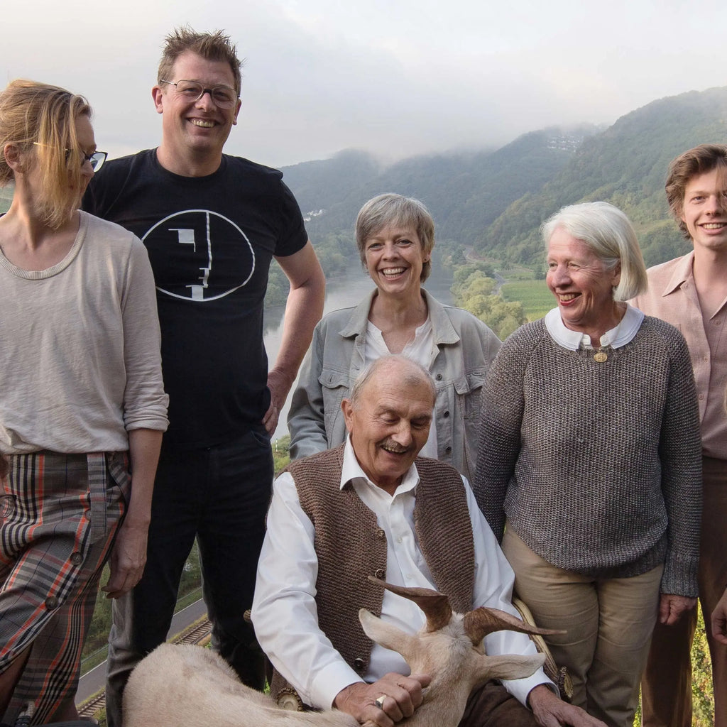 Wijnmakers van Weingut Melsheimer poseren met een fles Reiler Mullay-Hofberg Riesling Beerenauslese in de wijngaard in de Moezel, symbool voor ambachtelijke wijntraditie en passie voor duurzame Riesling-wijnen.